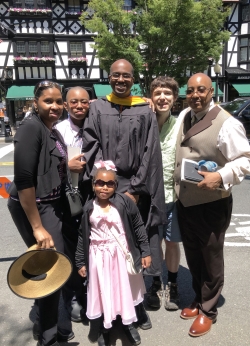 Lance Goodridge standing with his family and Lumbroso in front of Nassau street. Lance is wearing his black masters graduation gown.