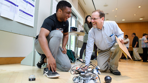 student and faculty with a robot